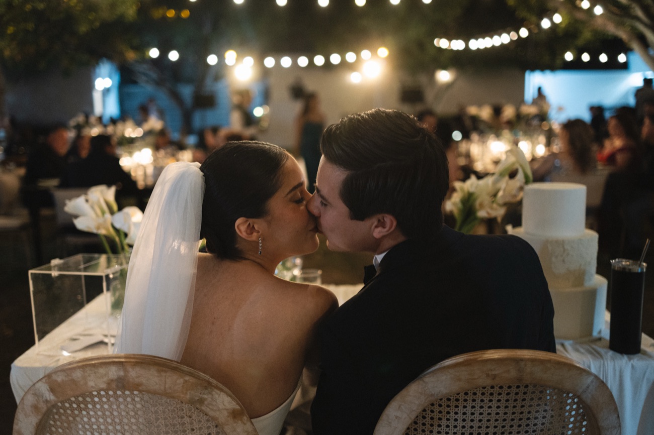 Novios besándose en la fiesta bajo luces colgantes