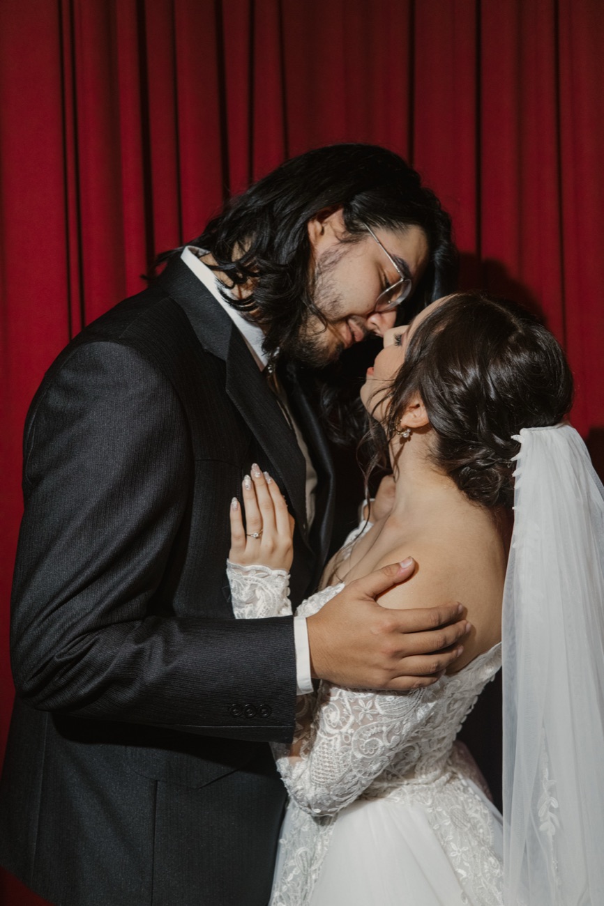 Los novios besándose sobre fondo rojo